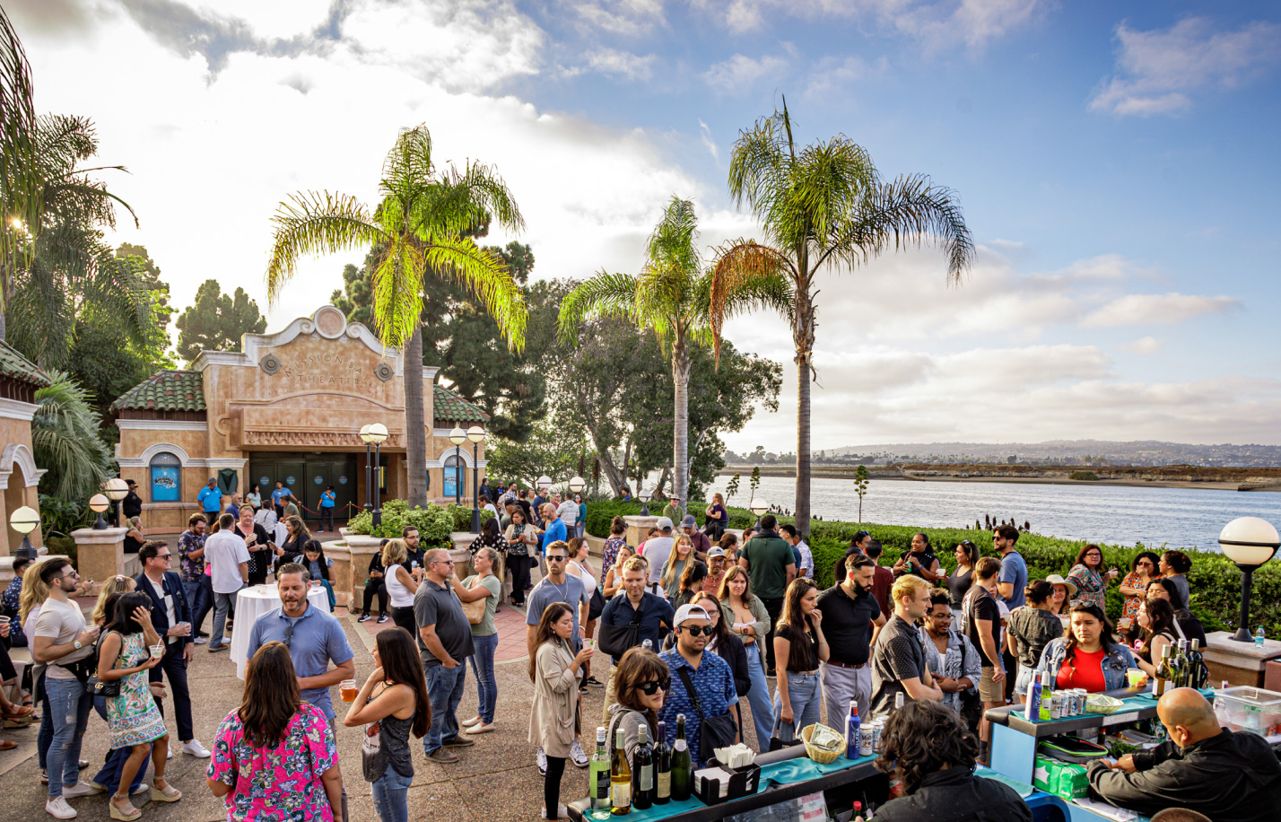 A crowd of people outside in front of a lake